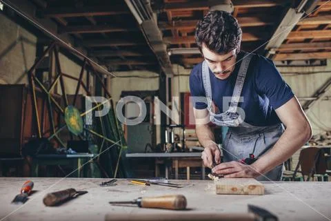 Carpenter using chisel on plank of wood in workshop Stock Photos
