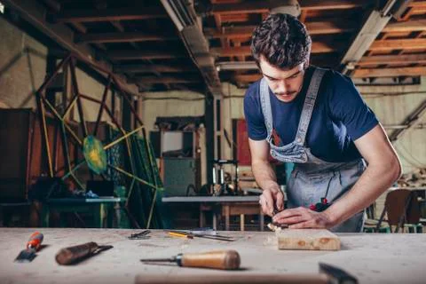 Carpenter using chisel on plank of wood in workshop Stock Photos