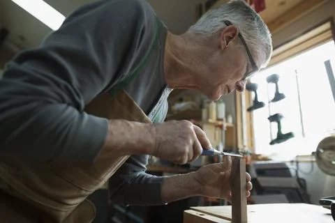 Carpenter using chisel on wood block in workshop Foto stock