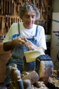 Carpenter using chisel on wooden mould for headwear in workshop Foto stock