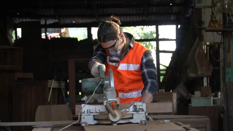 Carpenter using circular saw cutting wooden plank in workshop . Young man bui Stock Footage 158425208