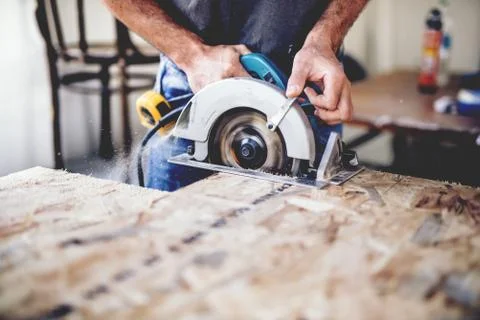 Carpenter using circular saw for cutting wooden boards. Construction details  Stock Photos