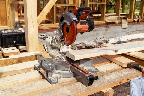 Carpenter using circular saw cutting wooden plank at construction site Stock Photos