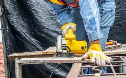 Carpenter using circular saw for cutting wooden boards with power tools, co.. Foto stock