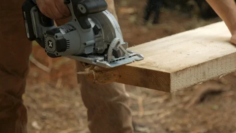 Carpenter using Circular Skill Saw Cutting Lumber in the wilderness in 4k Stock Footage 126728058