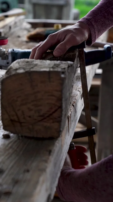 Carpenter using clamp to secure old timber beam for woodworking in workshop Видео 325204904