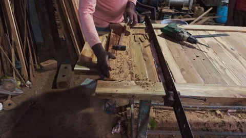 Carpenter using a clamp on wooden planks in a workshop with tools scattered.. Video stock 266864134