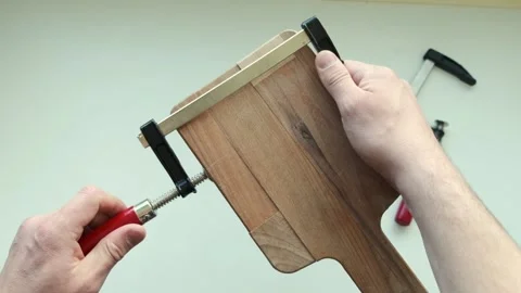 Carpenter using clamps to join and fasten a wooden timbers Stock Footage 243100410
