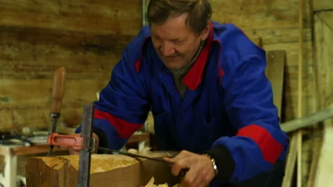Carpenter using a drawknife to carve wood into furniture Stock Footage 87560647