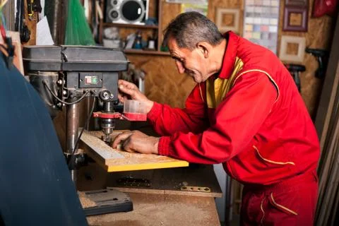 Carpenter using drill press to mae hole in wooden plank Foto stock