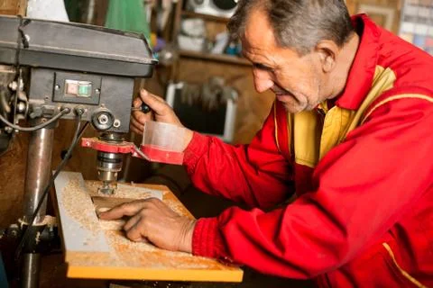 Carpenter using drill press to mae hole in wooden plank Stock-Fotos