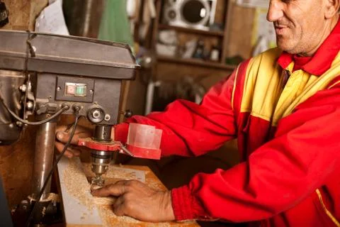 Carpenter using drill press to mae hole in wooden plank Stock Photos