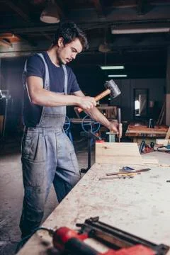 Carpenter using hammer and chisel on timber at workshop Stock Photos