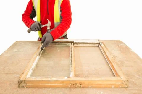 Carpenter using a hammer while repairing an old window frame sas Stock Photos