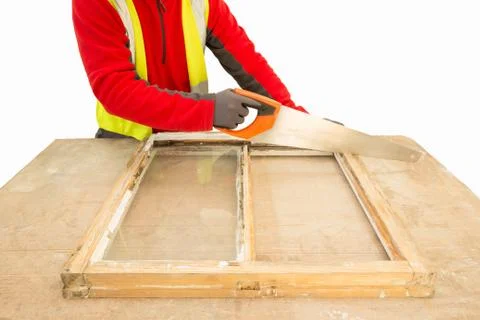 Carpenter using a handsaw while repairing an old window frame sa Stock Photos