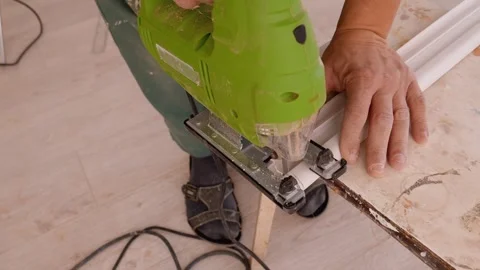 Carpenter using jigsaw for cutting white ceiling molding Stock Footage 326144867