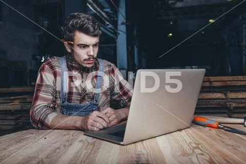 Carpenter using laptop while sitting in workshop Stock Photos