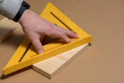 Carpenter using an old square to mark a diagonal line on a wood board Stock Photos