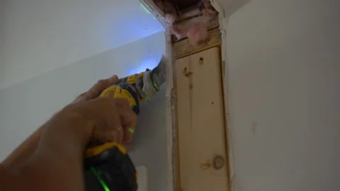 Carpenter using an oscillating power tool to cut drywall and wood around a door Stockbeeldmateriaal 346801826