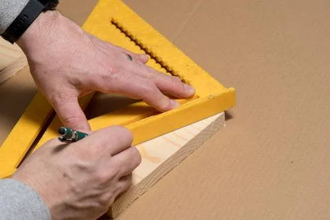 Carpenter using a pencil and old square marking a diagonal line on a wood board Stock Photos