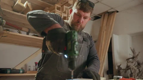 Carpenter using power drill to create precise joinery in workshop filled with Vidéo 348122502