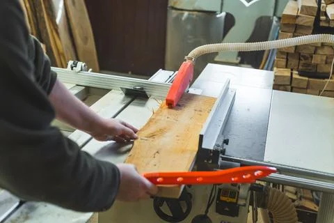 Carpenter using table saw blade to cut wooden plank while sliding it on a table Stock Photos