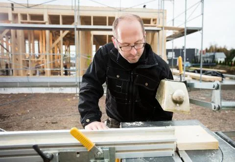 Carpenter Using Table Saw To Cut Plank At Site Stock Photos