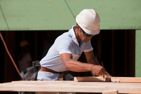 Carpenter using triangle to mark bevel cut line on rafter Stock Photos