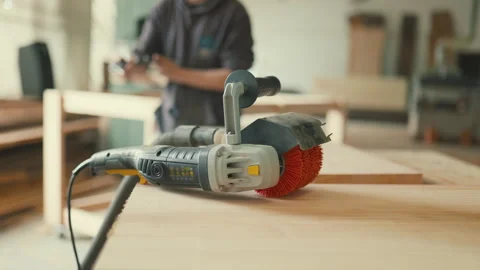 Carpenter using a vacuum cleaner after sanding wood in a workshop Stock Footage 335828096