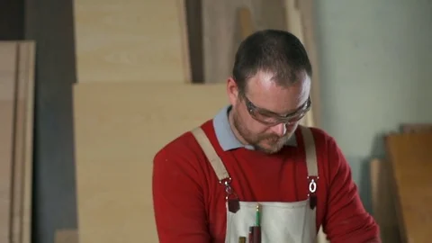 Carpenter wearing goggles polishing a table with an electric sander in workshop Stock Footage 74492273