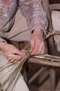 Carpenter weaves straw Stock Photos