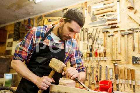 Carpenter with wood, hammer and chisel at workshop Stock Photos