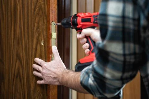 Carpenter at work repairs the door lock. Carpentry. Stock Photos