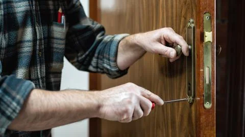 Carpenter at work repairs the door lock. Carpentry. Stock Photos