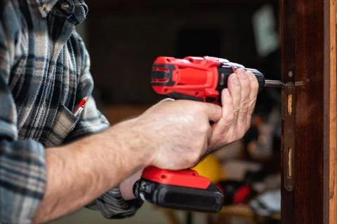 Carpenter at work repairs the door lock. Carpentry. Stock Photos
