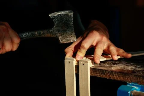 Carpenter at workbench nails down small wooden box.Hands of worker with old axe Stock Photos