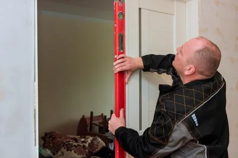Carpenter worker installation process of checks level correctness installation Foto stock