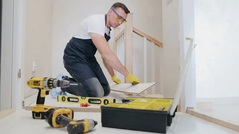 Carpenter worker installing laminate flooring in the corridor near the stairs Stock Footage 133359160