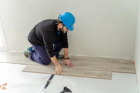 Carpenter worker installing laminate flooring in the room. Stock Photos