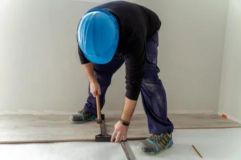 Carpenter worker installing laminate flooring in the room. Stock Photos