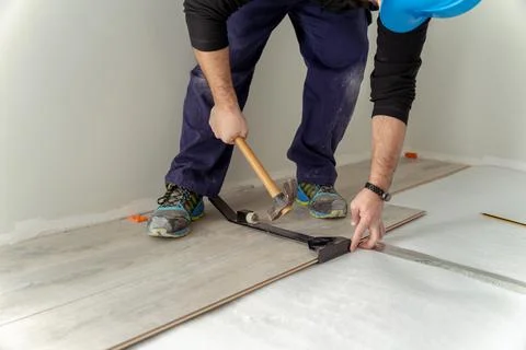 Carpenter worker installing laminate flooring in the room. Stock Photos