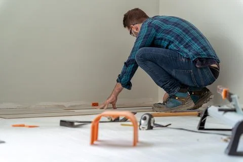 Carpenter worker installing laminate flooring in the room. Stock Photos