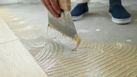 Carpenter worker putting glue on floor for parquet Stock Footage 85048708