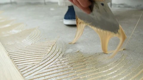Carpenter worker putting glue on floor for parquet Stock Footage 85048876