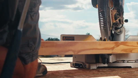A carpenter working on a construction project carefully uses a sharp chop saw Vídeos de archivo 308723279