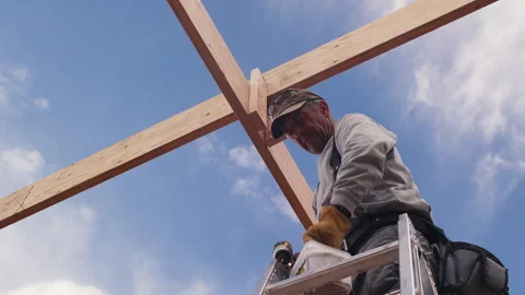 A carpenter working on a construction project stands on a ladder and then Stock Footage 308723216