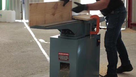 Carpenter working on an Electric Benchtop Jointer cutting wooden board Stock Footage