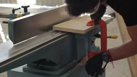 Carpenter working on an Electric Benchtop Jointer cutting a wooden board Stock Footage