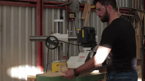 Carpenter working on a machine cutting a wooden board in a carpentry workshop Video stock 173940399