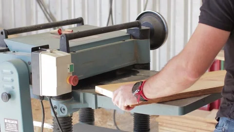 Carpenter working on a Thickness Planer machine cutting a wooden plank Video stock 173930825